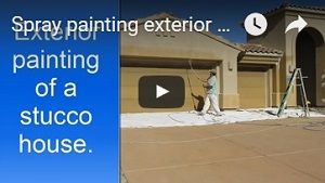 Spray painting exterior of a stucco house.